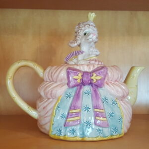 Vintage ceramic teapot by Fitz and Floyd depicting a white poodle in a royal pink and blue gown with a crown, labeled “Madame Pompidog.”