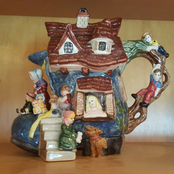 Colorful ceramic teapot shaped like a storybook house with children, representing the Old Woman in a Shoe by Fitz and Floyd, 1995 limited edition.