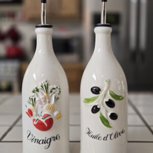 A pair of 12" tall Revol France oil and vinegar bottles with hand-painted sculptural designs and embossed French labels.