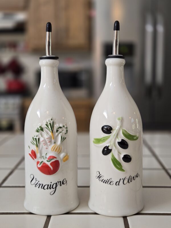 A pair of 12" tall Revol France oil and vinegar bottles with hand-painted sculptural designs and embossed French labels.